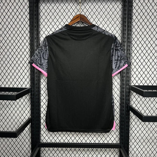 Maillot de football noir et gris avec motifs, détails rose, suspendu sur un cintre en bois
