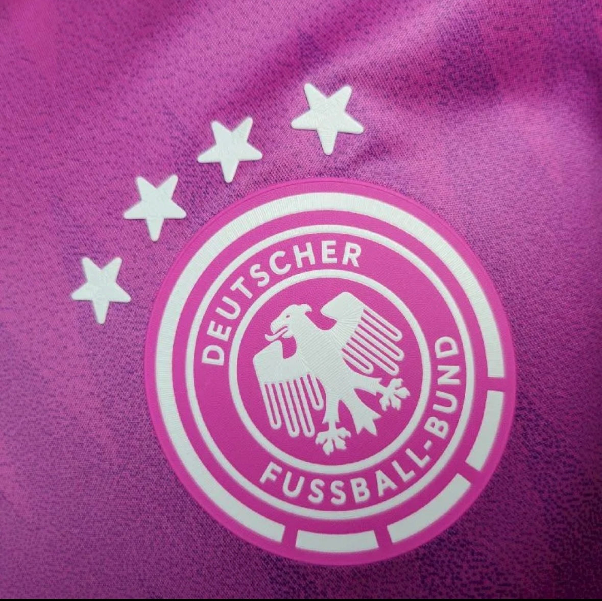 Logo Deutscher Fussball-Bund blanc sur fond violet avec quatre étoiles au-dessus