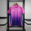 Maillot de football équipe allemande rose et violet avec logo Adidas suspendu sur grille métallique