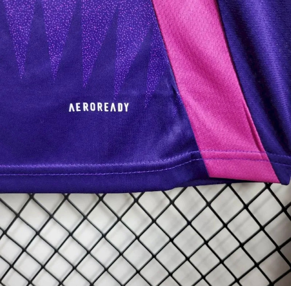 Détail d'un textile AEROREADY violet et rose sur fond en treillis noir