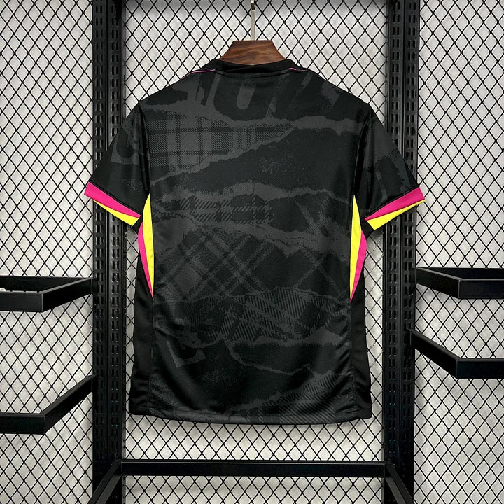 Maillot de football Chelsea 2024-2025 troisième tenue, noir avec détails roses et jaunes, suspendu sur grille métallique