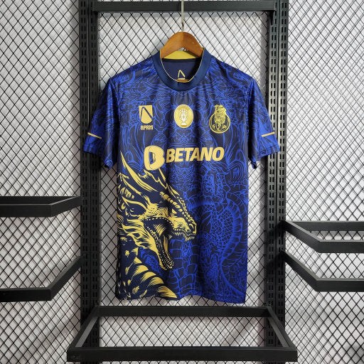 Maillot de football bleu foncé avec motif dragon doré et logos Betano, exposé sur un cintre noir