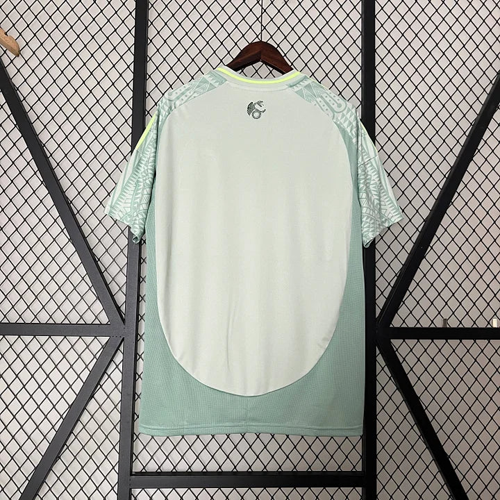 Maillot de football vert clair du Mexique 2024-2025 avec motifs blancs suspendu sur un grillage noir