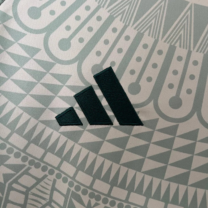 Logo Adidas noir brodé sur tissu de maillot de football vert avec motif géométrique détaillé