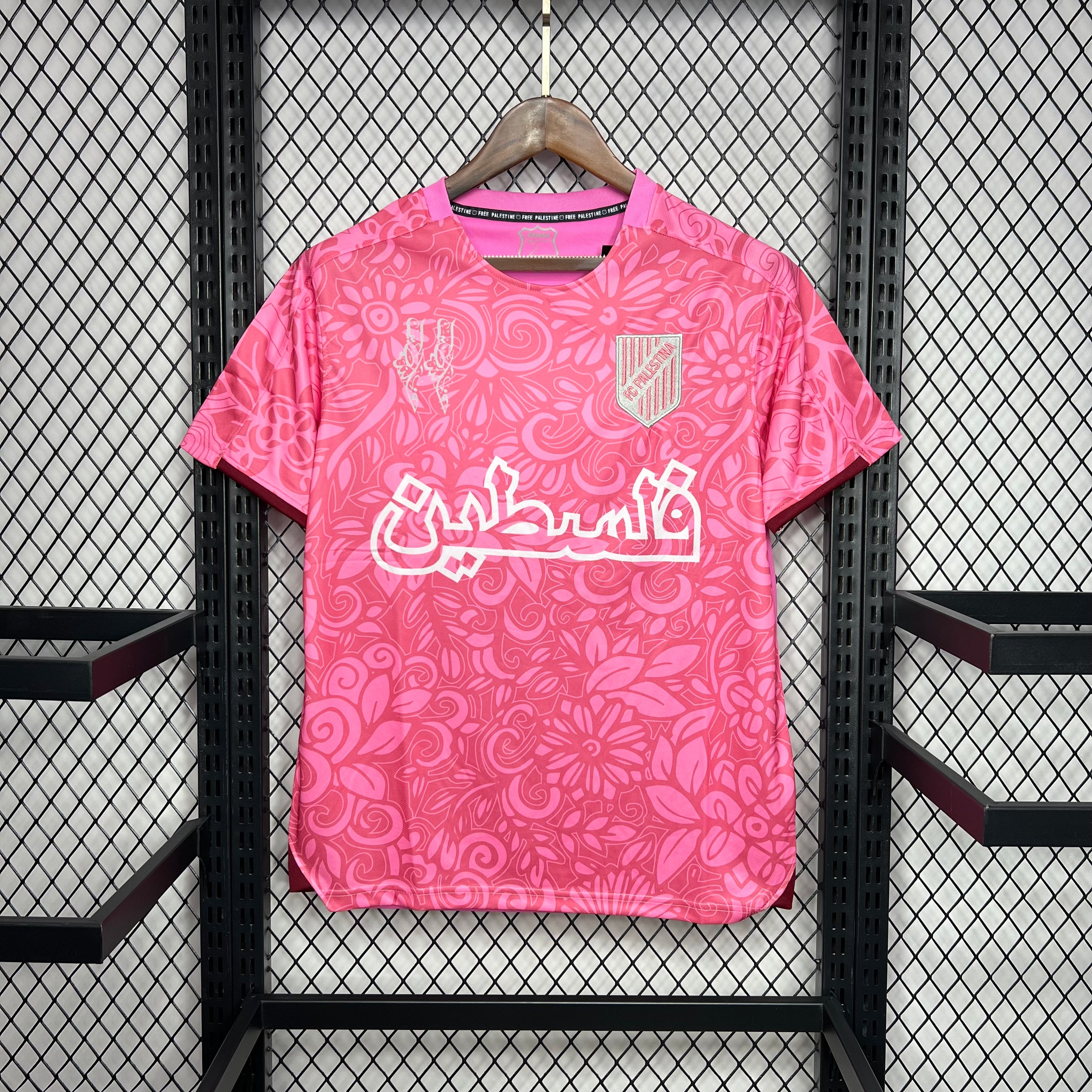 Maillot de football rose 2024 FC Palestine avec motifs floraux et texte arabe accroché sur grille