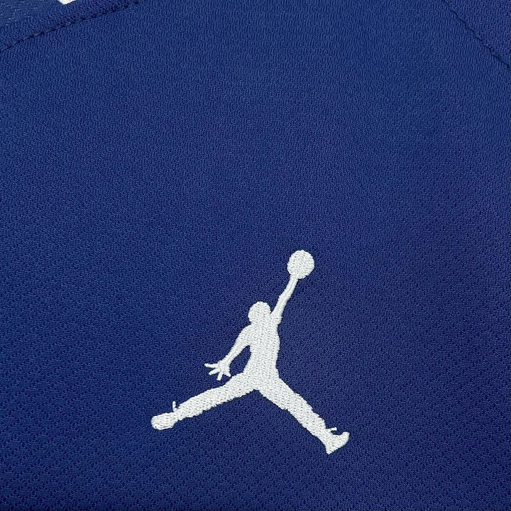 Logo Jordan blanc brodé sur tissu texturé bleu marine, maillot Paris Saint-Germain PSG
