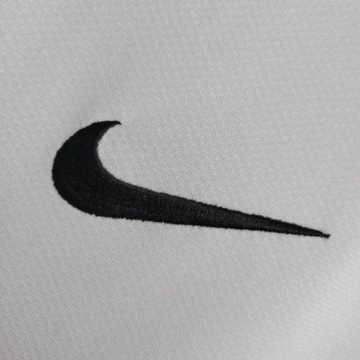 Logo Nike noir brodé sur tissu blanc uni, détail textile proche